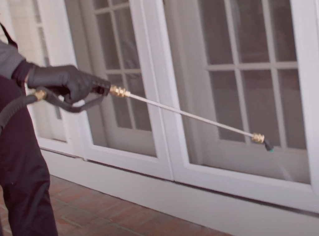 Exterminator applying exterior pest spray to door frames as part of Pest Control in East Lansing.